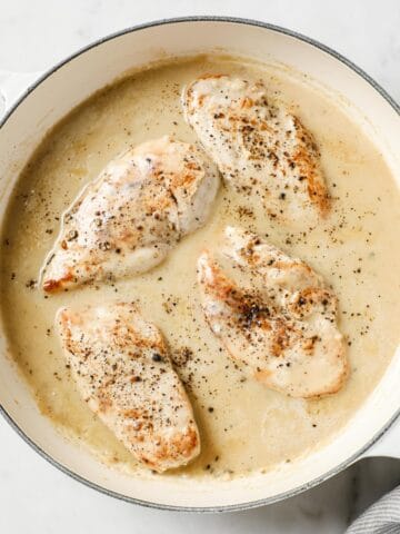 overhead of a creamy garlic sauce for chicken in a pan with cooked chicken inside