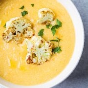 large bowl of cauliflower soup topped with roasted cauliflower florets