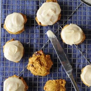 pumpkin cookies being frosted with cream cheese icing
