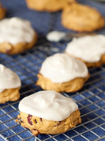 pumpkin cookies on a cooling rack frosted with cream cheese icing