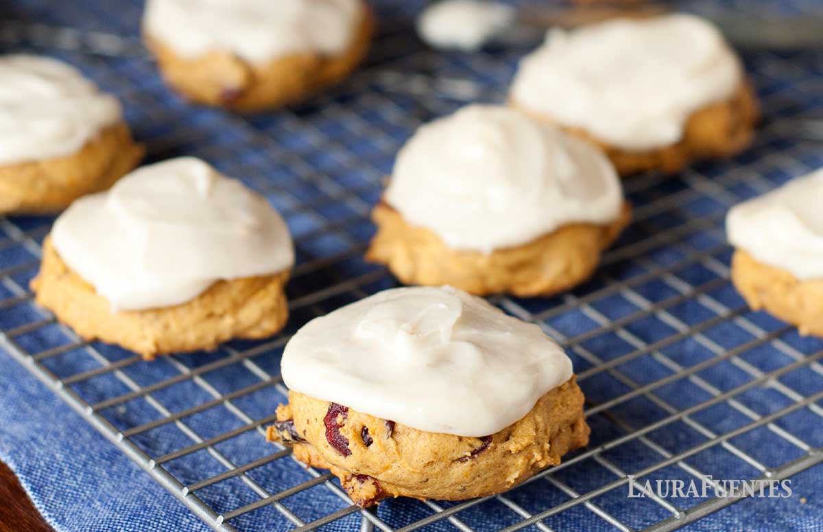 pumpkin cookies on a cooling rack frosted with cream cheese icing