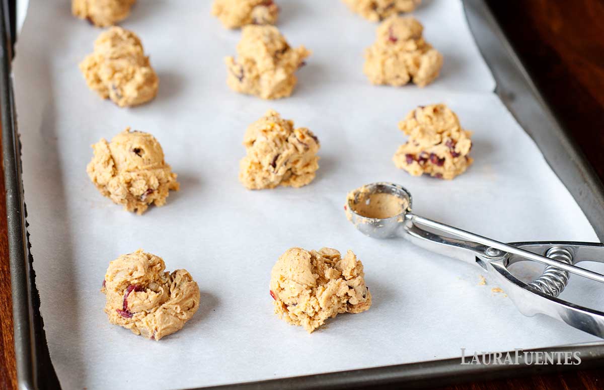 pumpkin cookies being scooped onto a baking sheet with cookie scooper