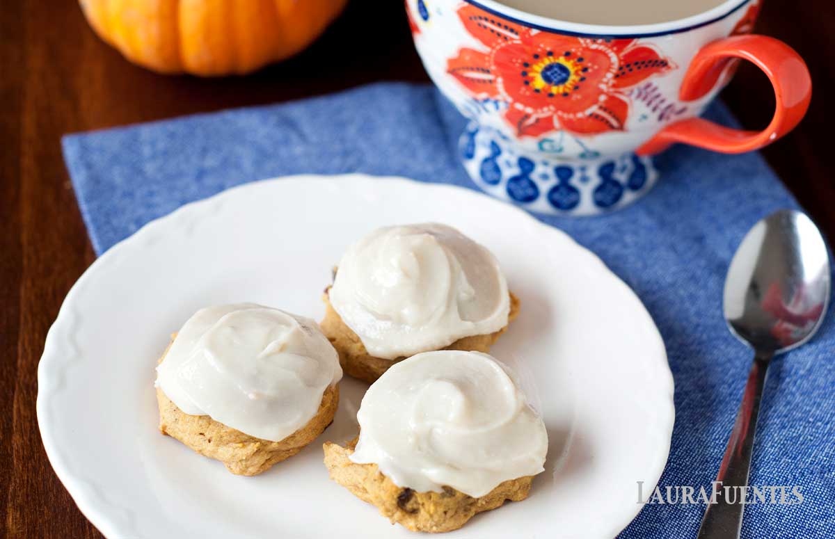 three pumpkin cookies with cream cheese frosting on a plate