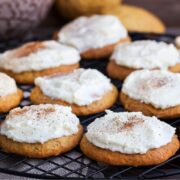 pumpkin cookies with cream cheese frosting sitting on a wire rack