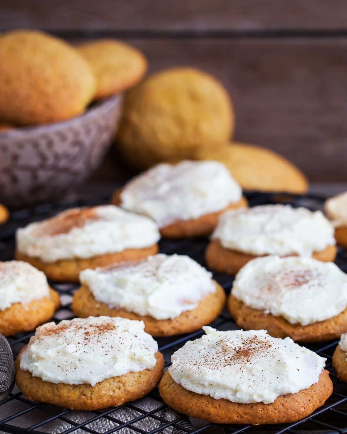 pumpkin cookies with cream cheese frosting sitting on a wire rack