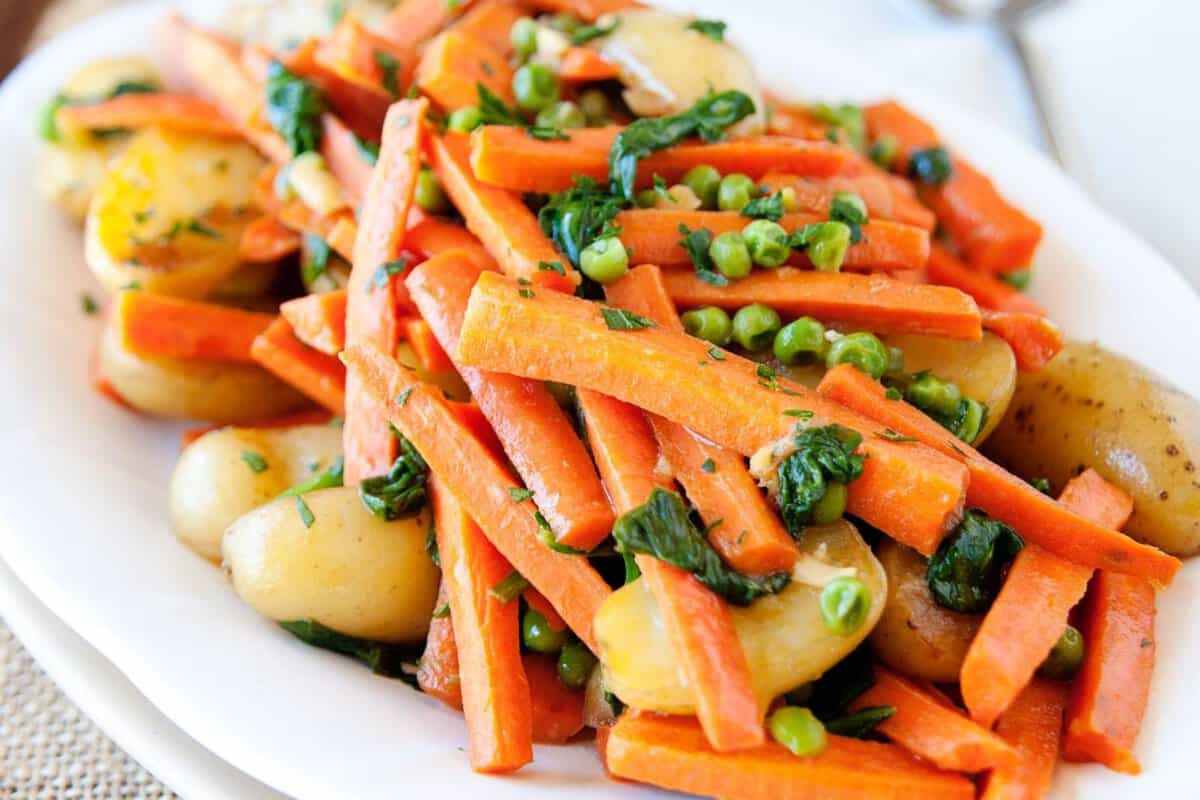 large serving dish of carrots, peas and potatoes