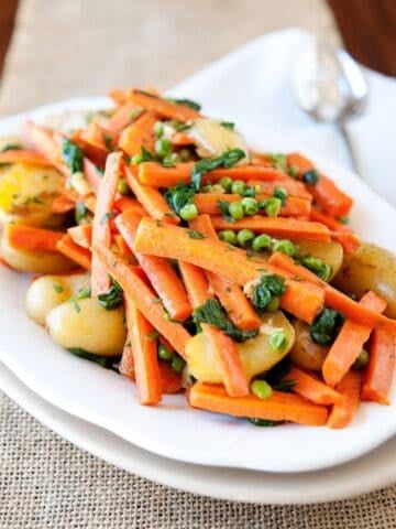 large serving dish of carrots, peas and potatoes