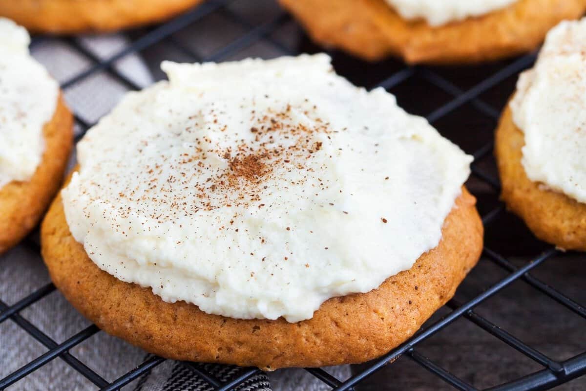 Frosted pumpkin Cookies close up view of pumpkin cookies with cream cheese frosting sitting on a wire rack