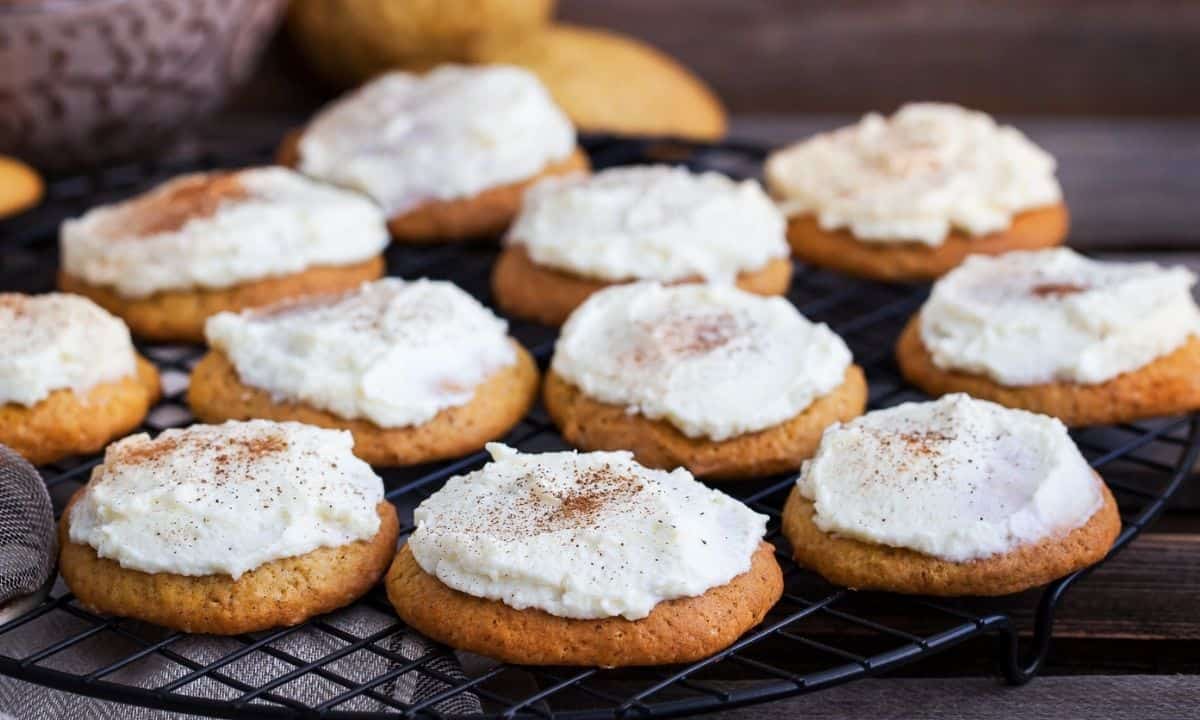 pumpkin cookies with cream cheese frosting sitting on a wire rack