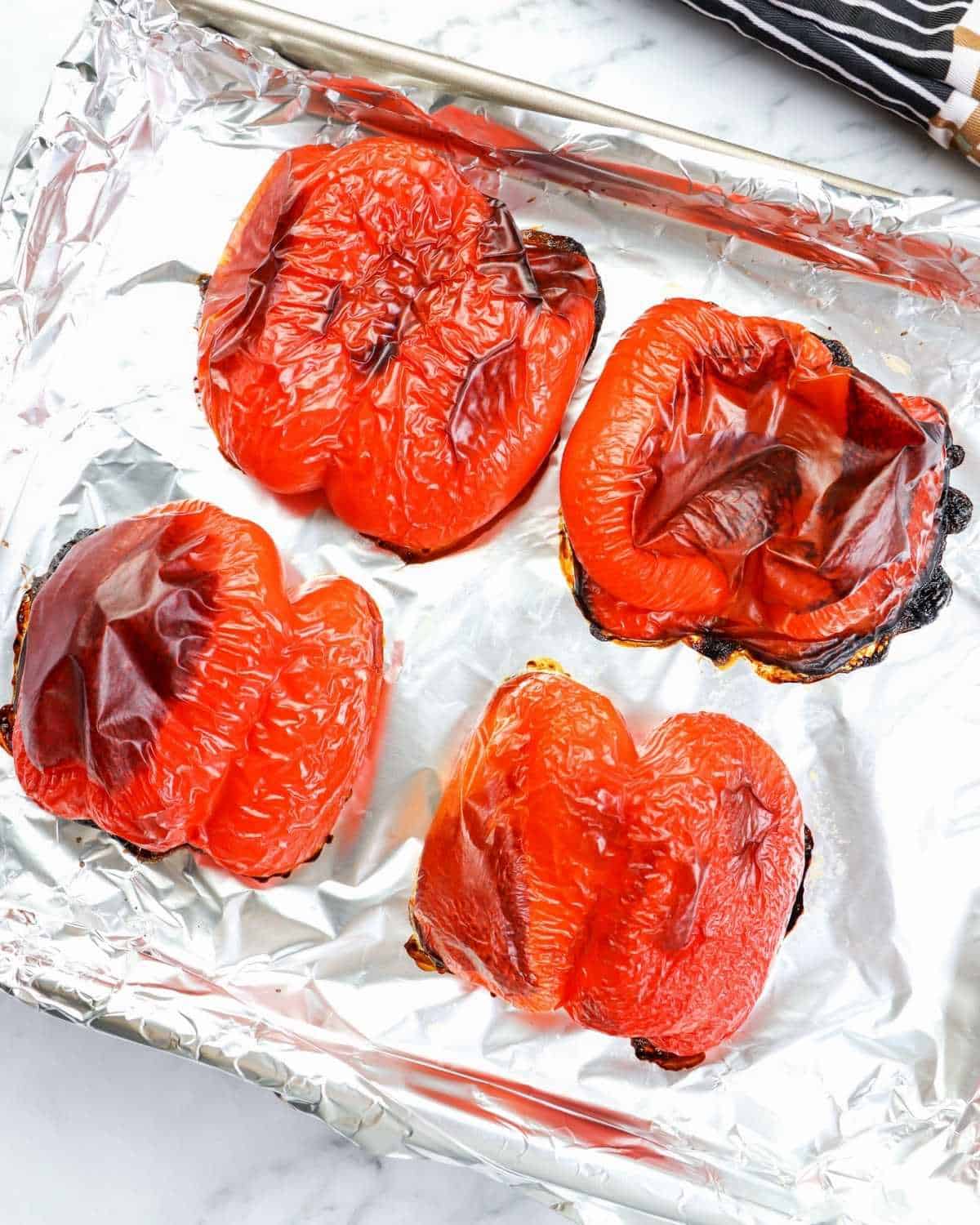 overhead view of roasted red peppers in a lined baking sheet