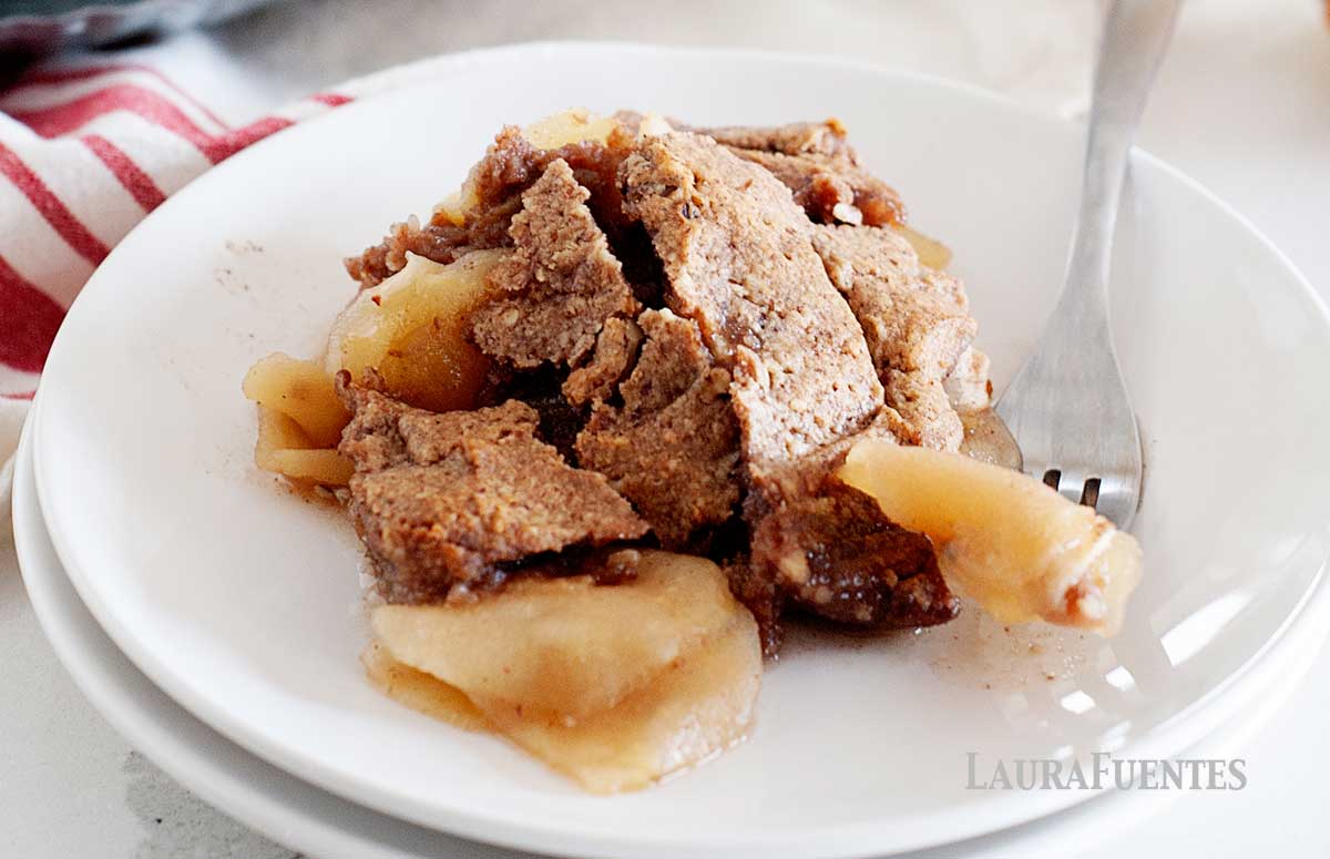 plate of gluten free apple crisp with a large baking dish in the background