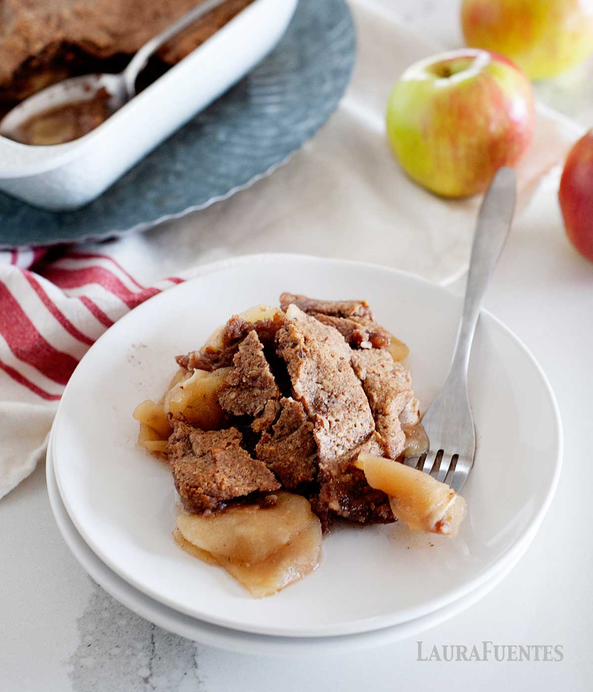plate of gluten free apple crisp with a large baking dish in the background