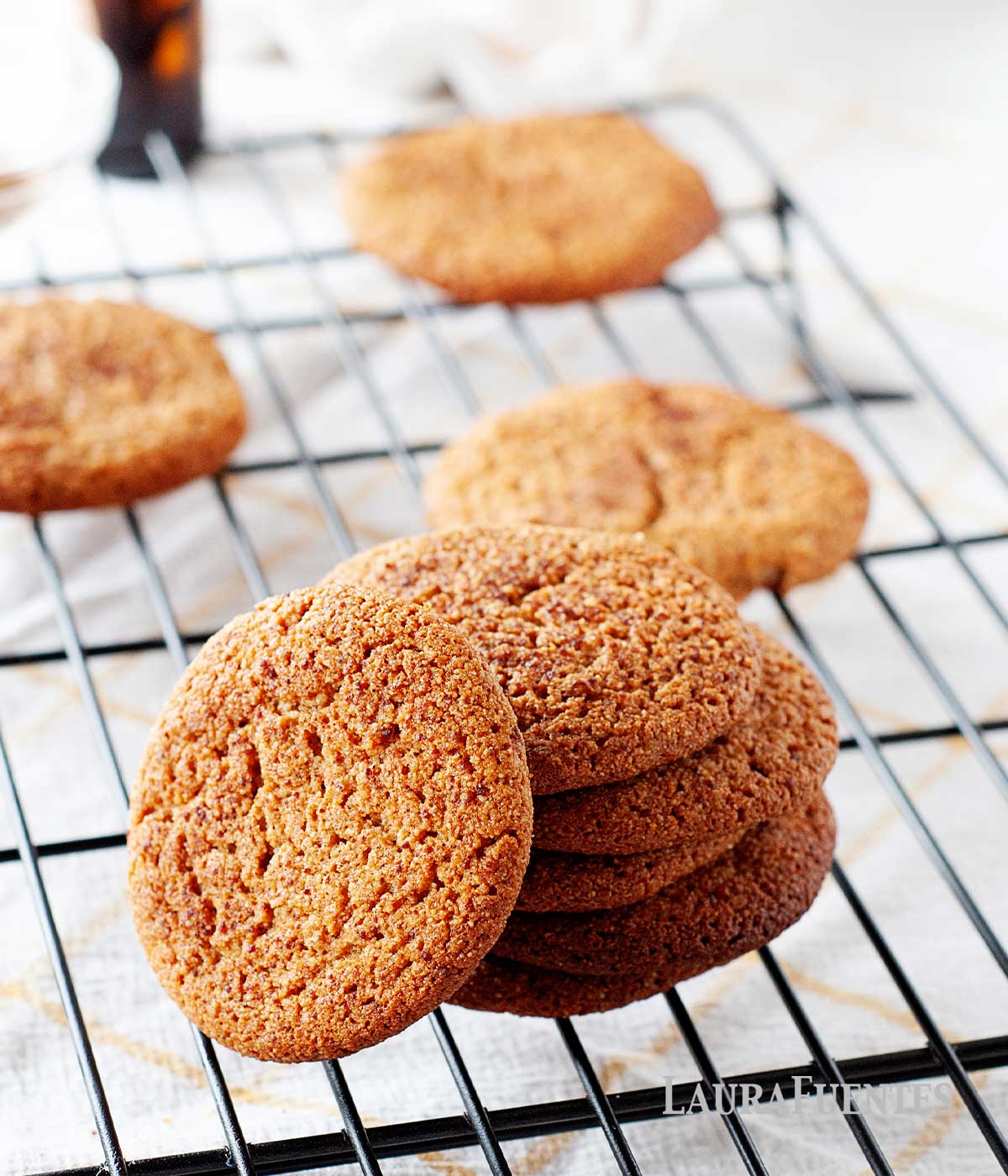 stack of gluten free snickerdoodles on a cooling rack with more cookies in the background