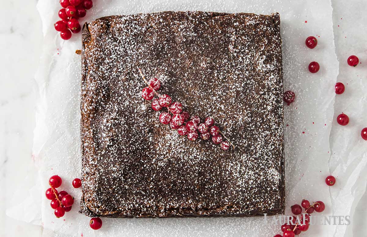 large square gingerbread cake topped with powdered sugar and craberries