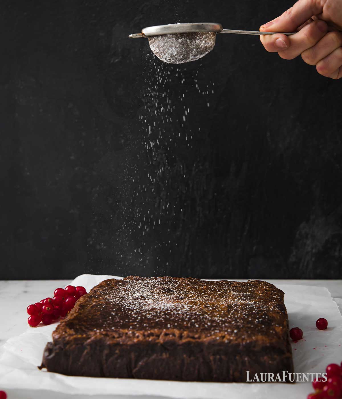 sprinkling powdered sugar over a square cake from a mini sifter
