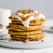 Stack of peanut butter pancakes topped with whipped cream and more peanut butter on top.