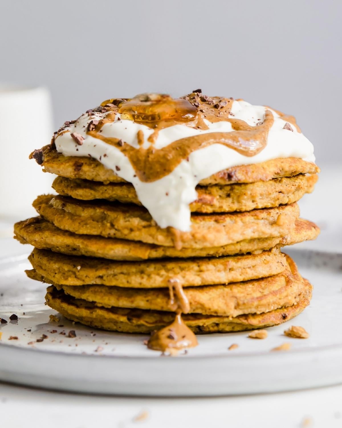 Stack of peanut butter pancakes topped with whipped cream and more peanut butter on top.