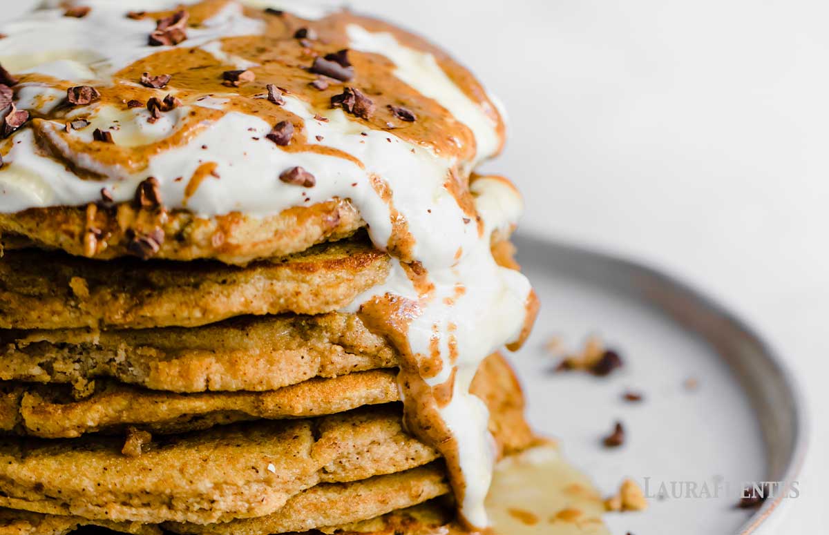large stack of peanut butter pancakes topped with whipped cream and peanut butter