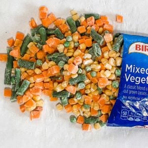 frozen bag of vegetables pouring onto a baking sheet for roasting