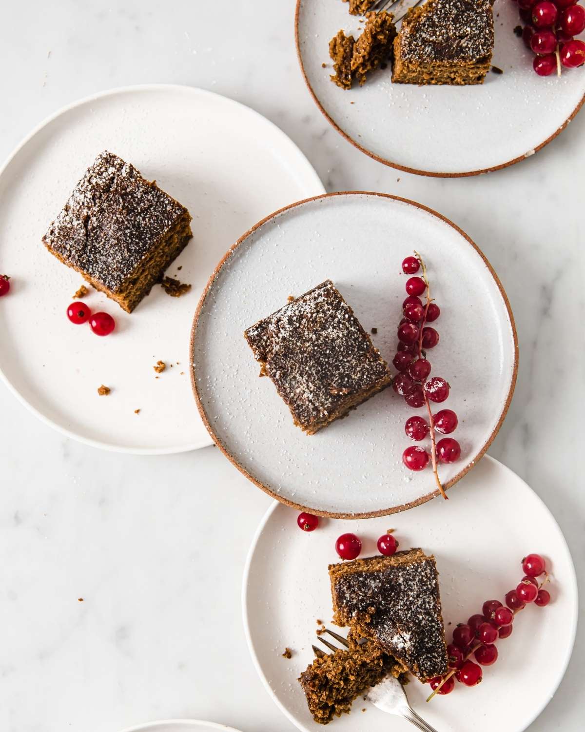 top view of four plates with a square of gingerbread cake