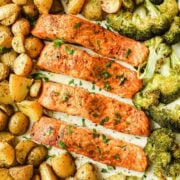 overhead view of baked salmon and potatoes on a sheet pan with broccoli too