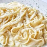 close up view of fettuccini in a homemade Alfredo sauce made with cream on a plate