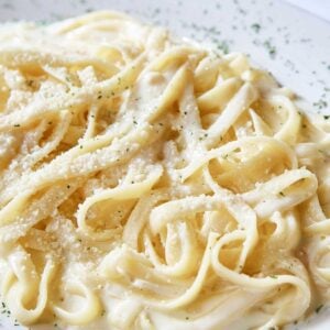 close up view of fettuccini in a homemade Alfredo sauce made with cream on a plate
