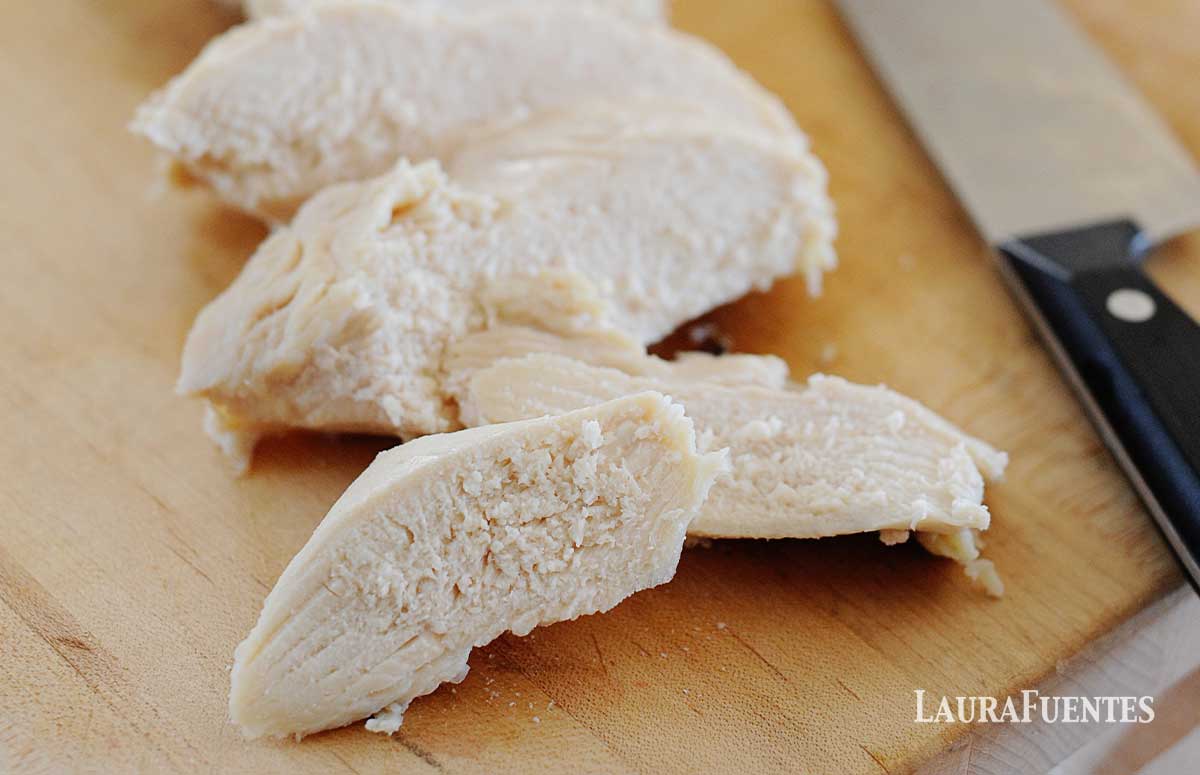 sliced poached chicken breast on a cutting board