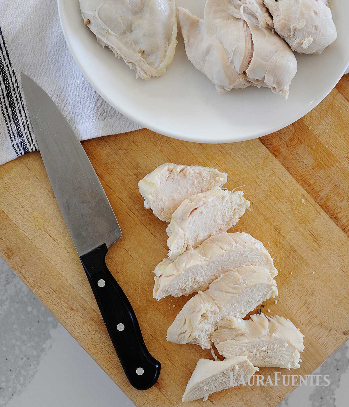 poached chicken on a plate and being sliced on a cutting board