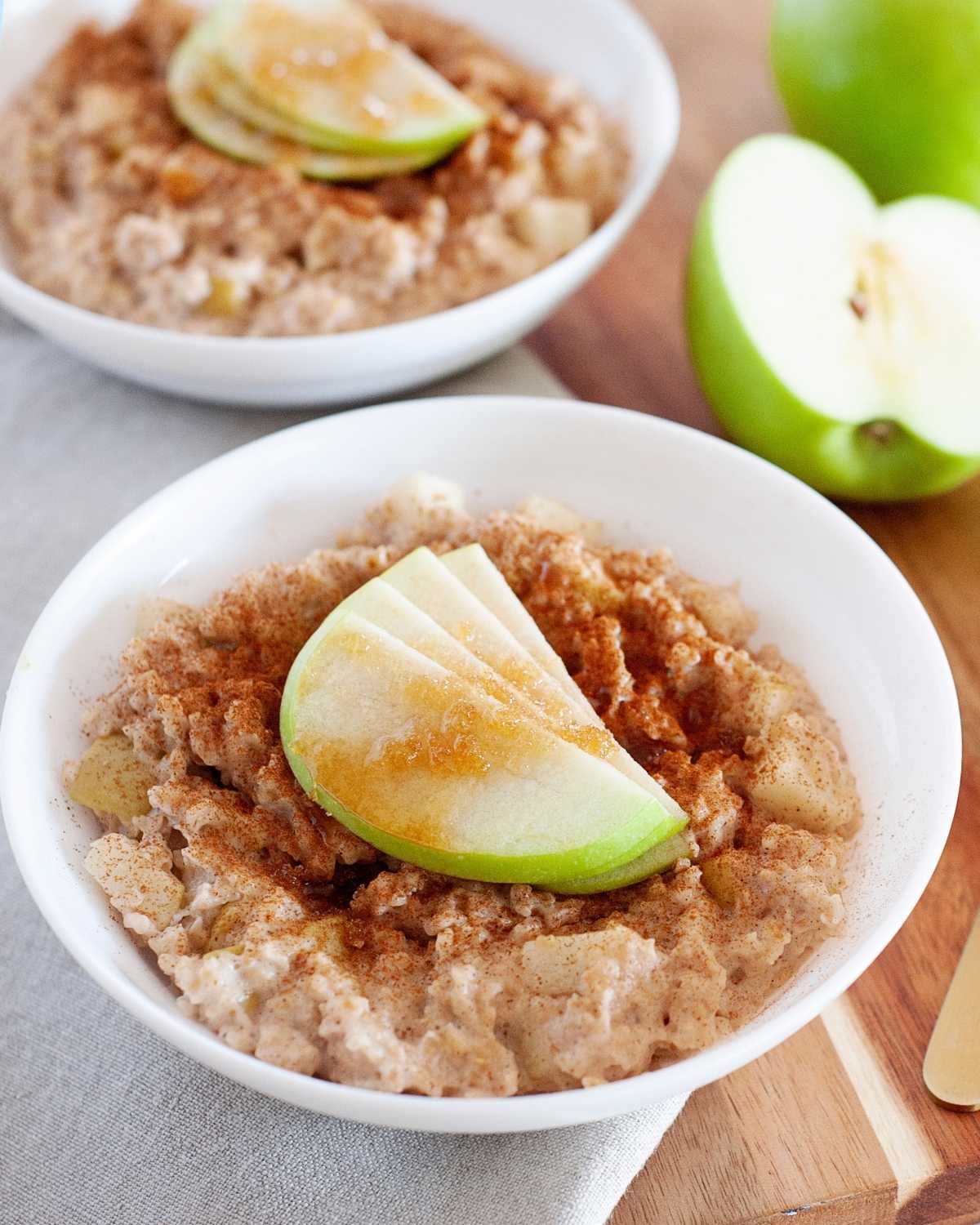 two large bowls of oatmeal topped with cinnamon and sliced green apple