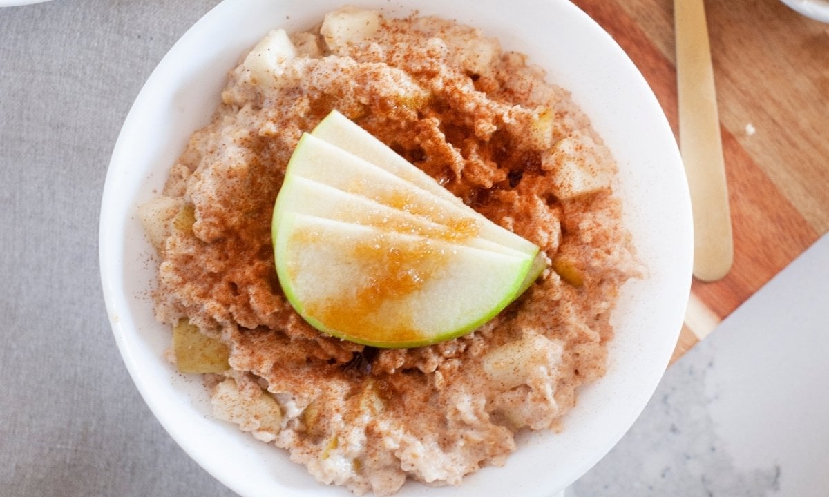 overhead view of oatmeal in a bowl topped with cinnamon and sliced apples