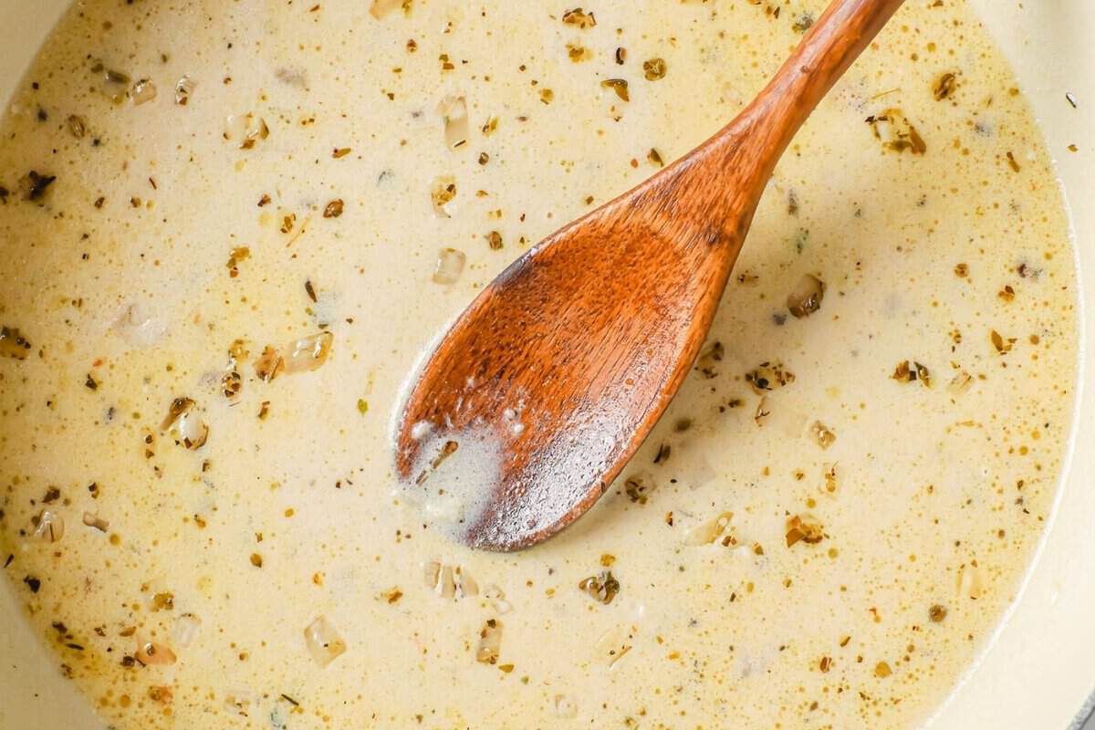 overhead view of lemon garlic sauce in a skillet with a wooden spoon inside