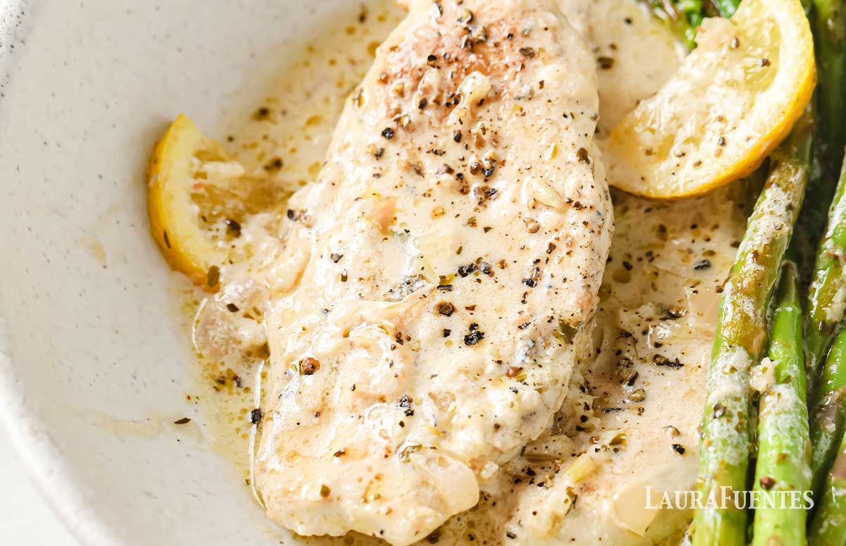 closeup of chicken and asparagus on a plate covered with lemon garlic sauce