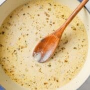 overhead view of lemon garlic sauce in a skillet with a wooden spoon inside
