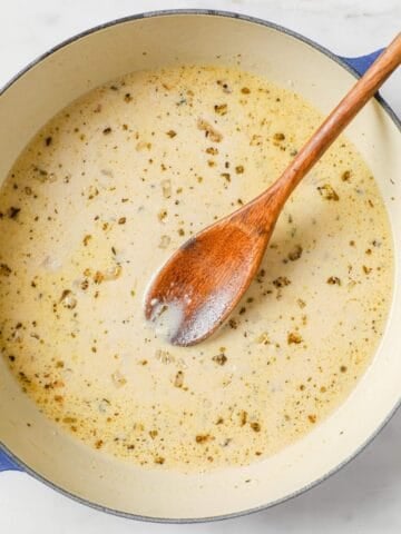 overhead view of lemon garlic sauce in a skillet with a wooden spoon inside