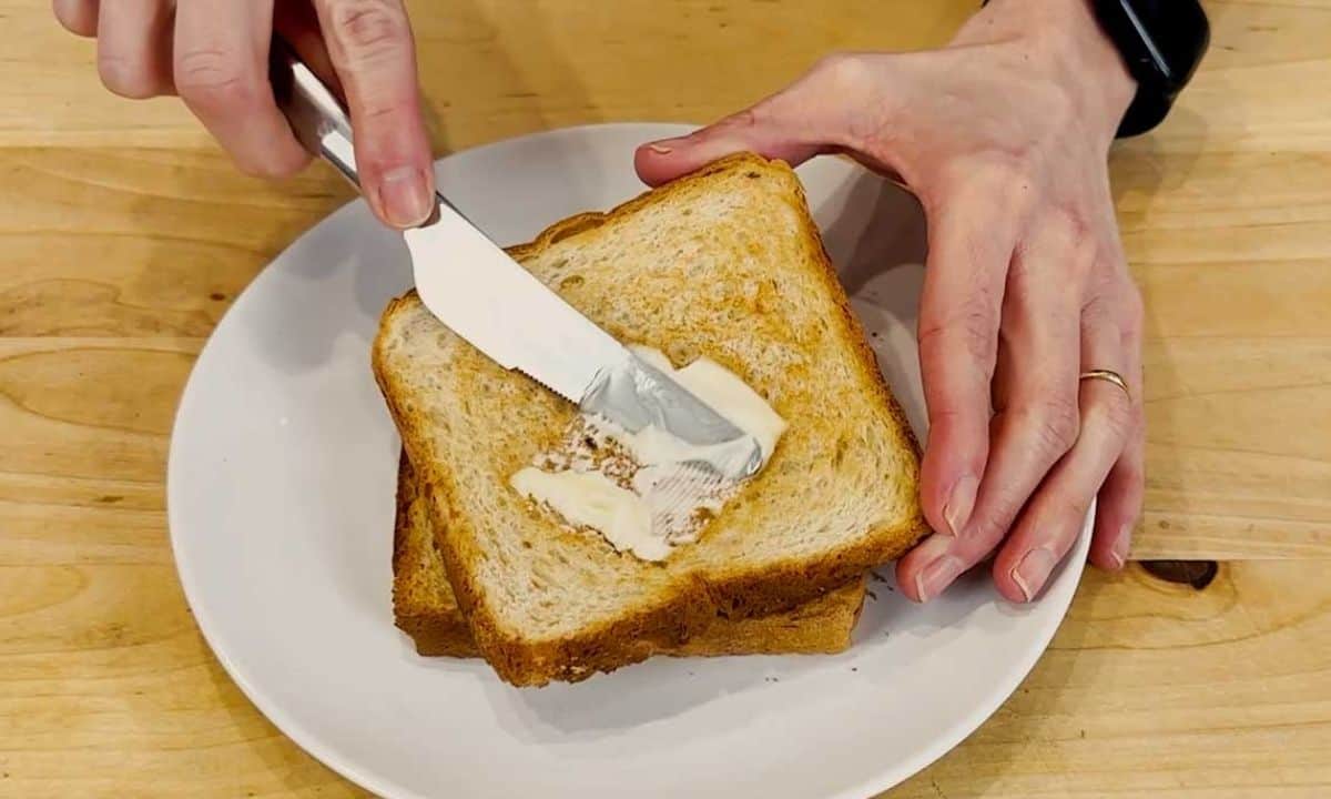 a person spreading butter over a toast