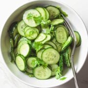 sliced cucumber salad in a white bowl