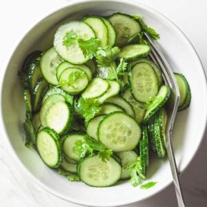 sliced cucumber salad in a white bowl