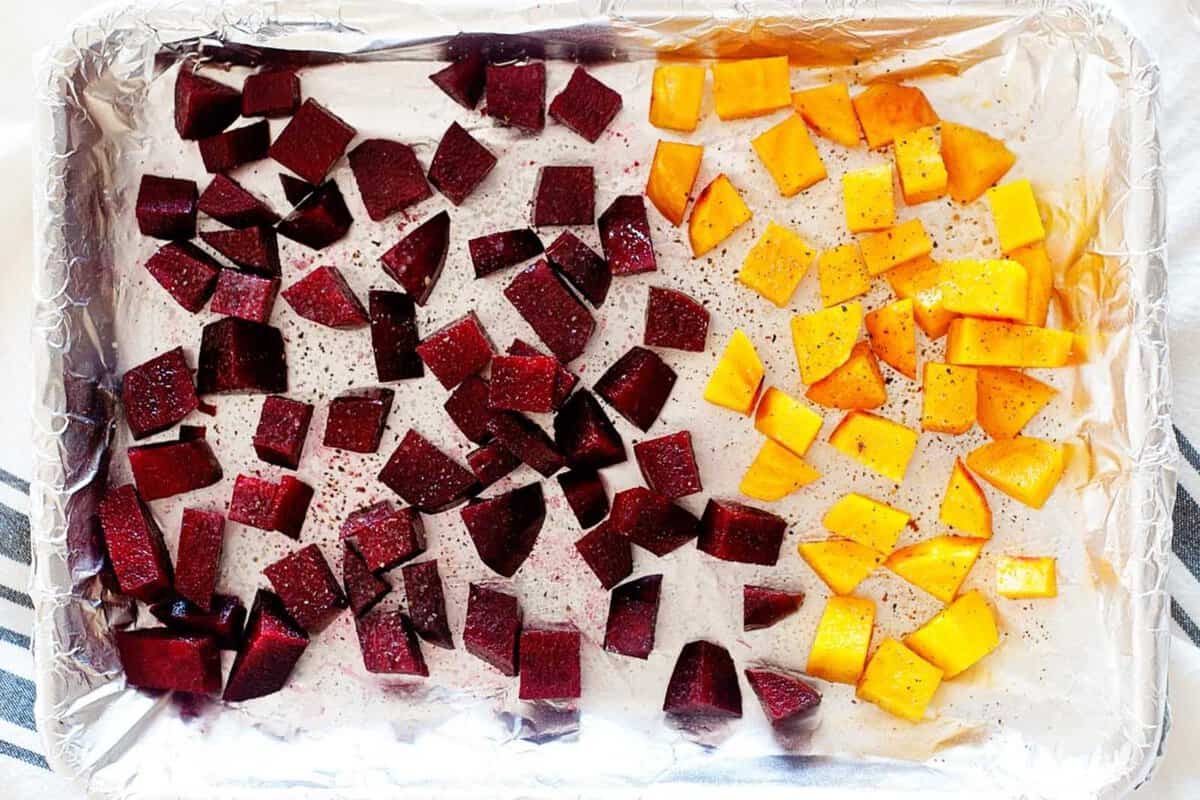 roasted cubed beets and butternut squash in a lined baking sheet