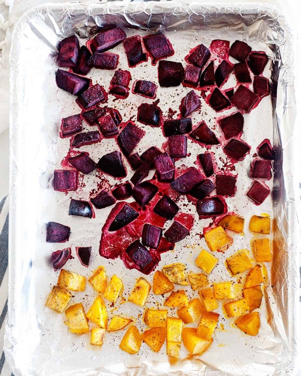 roasted cubed beets and butternut squash in a lined baking sheet