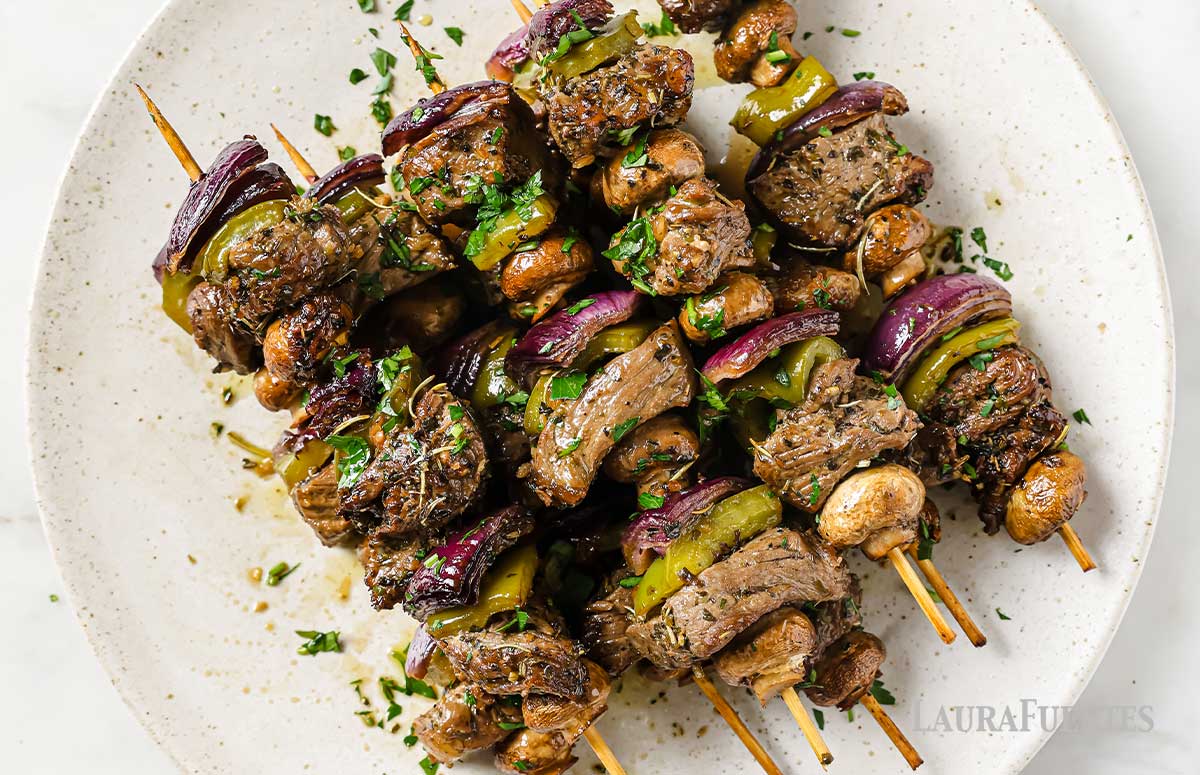 four beef skewers on a plate