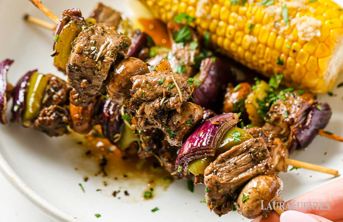 steak kebabs and corn on the cob on a plate
