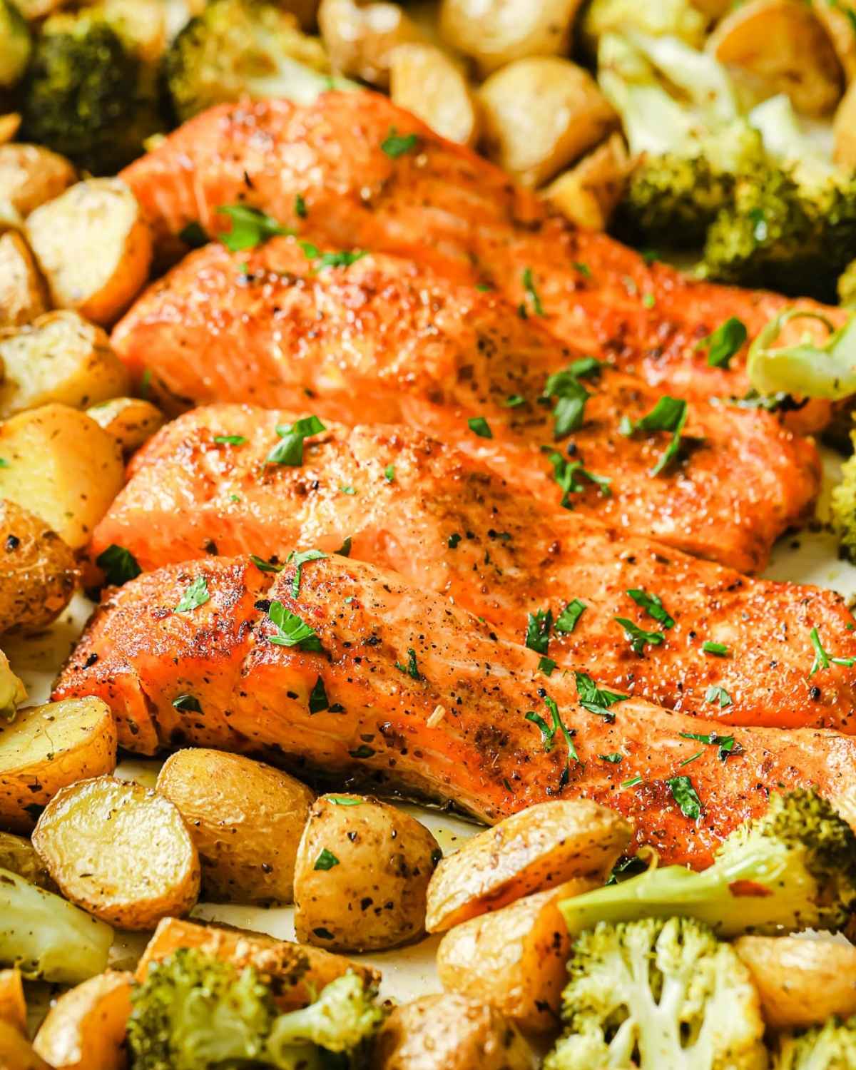 baked cajun salmon fillets with baby potatoes and broccoli in a baking dish