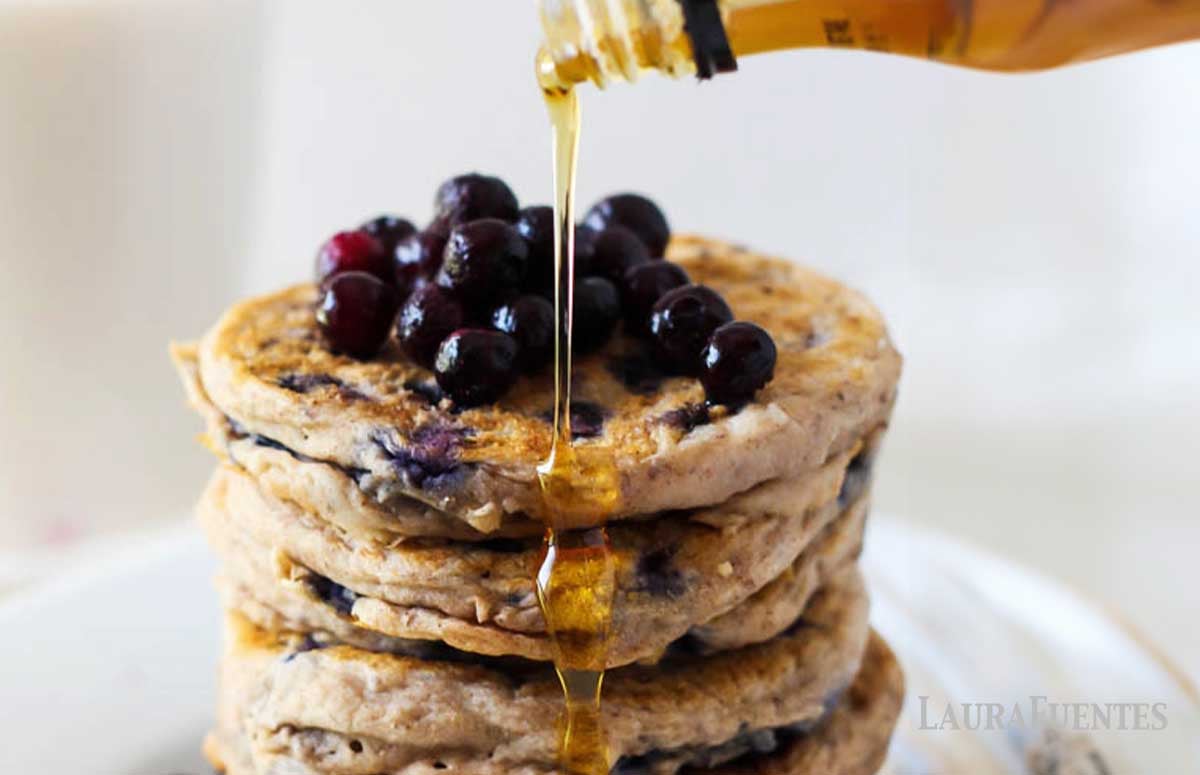 a stack of GF blueberry pancakes with blueberries and syrup over it.