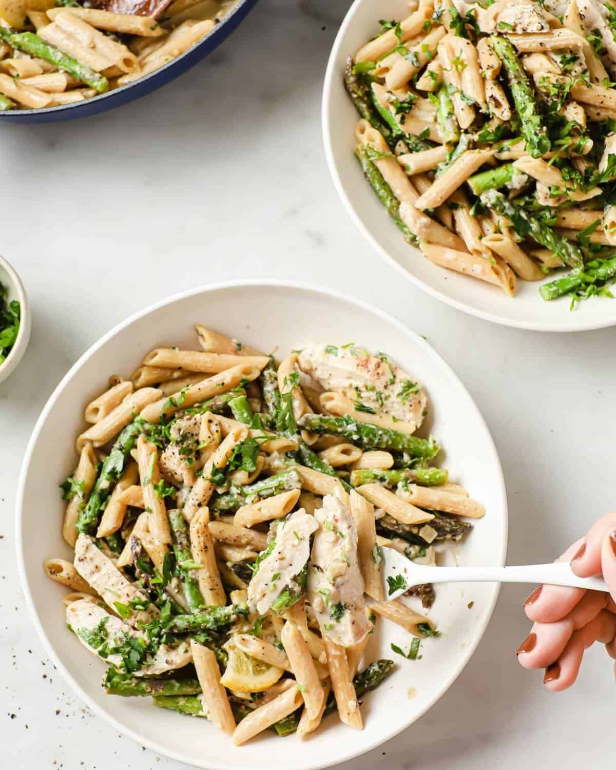plated garlic lemon chicken pasta recipe with a hand holding a fork to taste