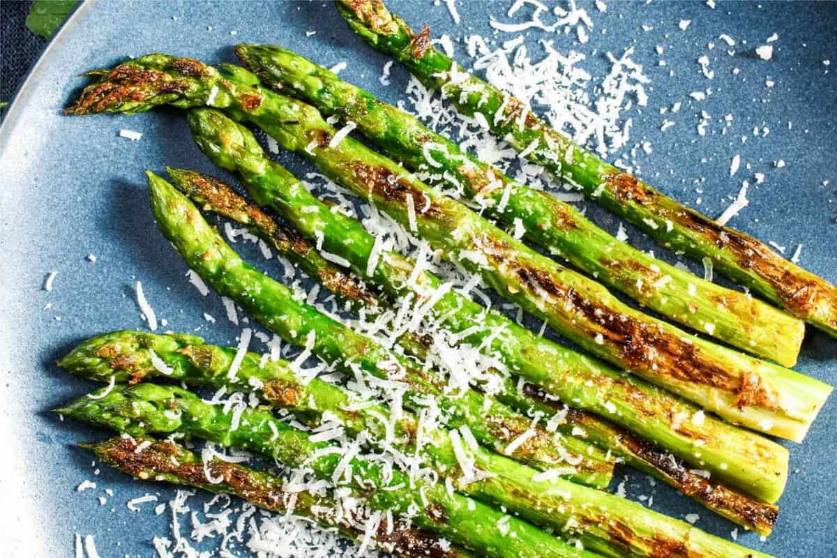 Roasted asparagus spears on a blue plate, topped with Parmesan cheese