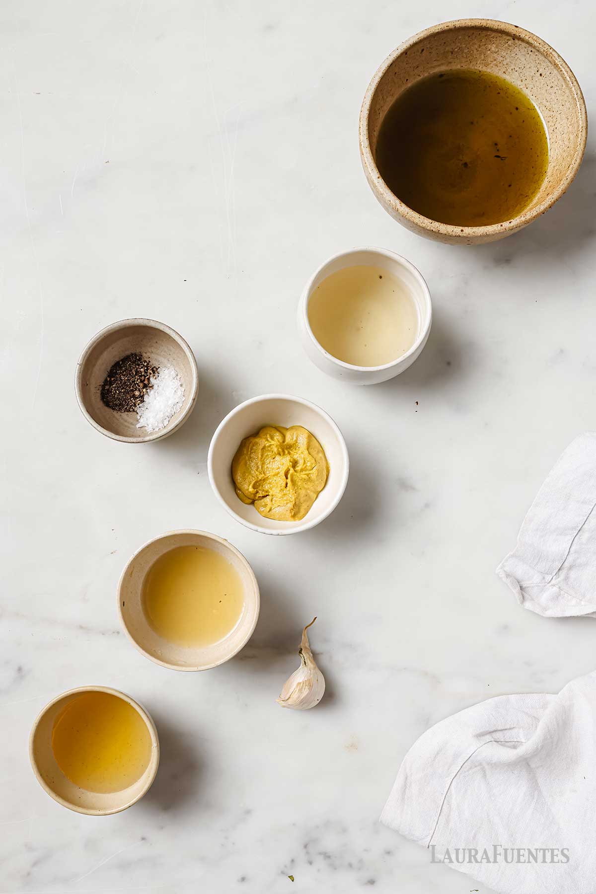 bowl with honey, oil, vinegar, mustard, lemon juice, salt, pepper and a garlic clove.