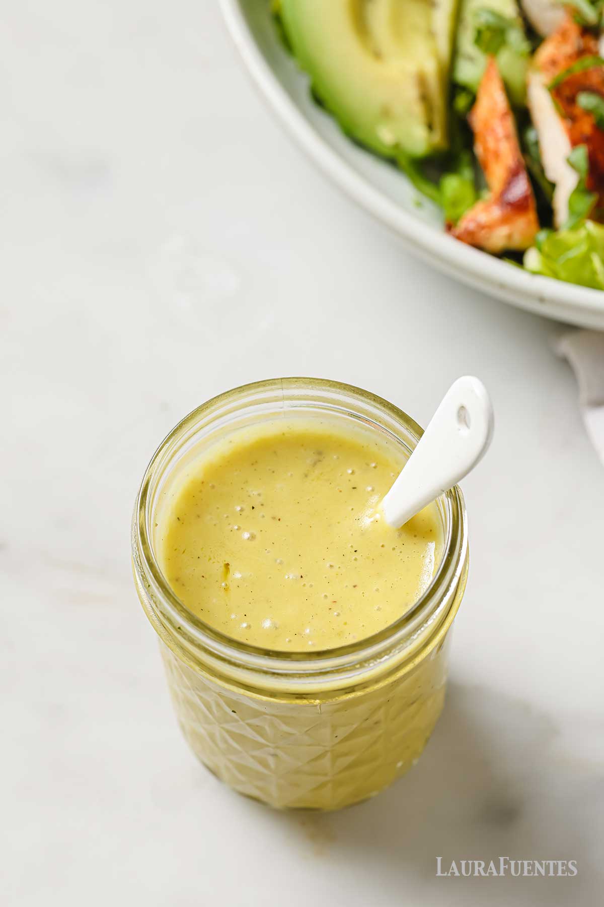 champagne vinaigrette in a jar with a spoon inside.