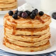 large stack of greek yogurt pancakes topped with blueberries, yogurt and syrup