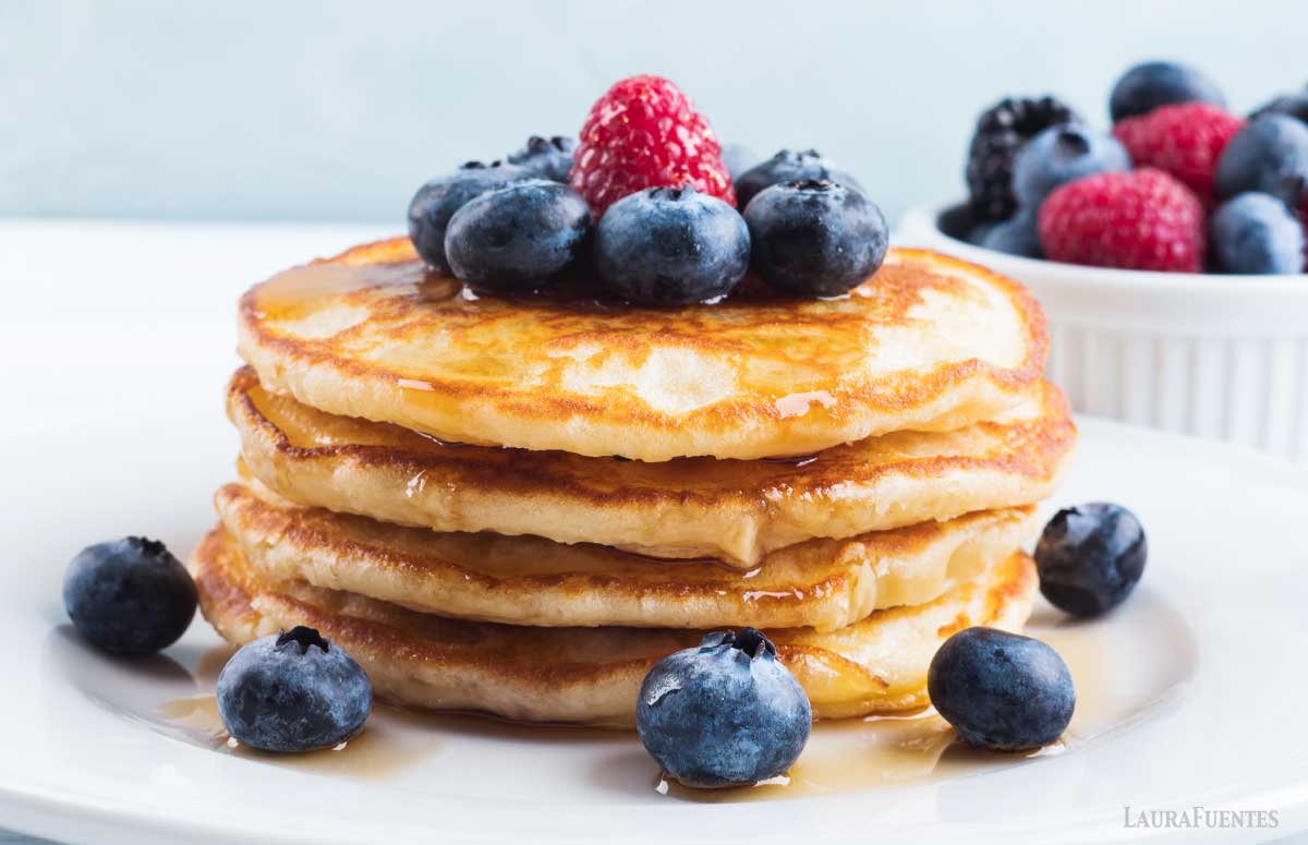 stack of pancakes made with greek yogurt on a plate with blueberries and raspberries